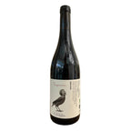 A dark glass wine bottle with a white label featuring a black bird illustration and the text 'Sapere sine' and 'Cuvier Brothers', standing on a cardboard box against a beige tent backdrop.