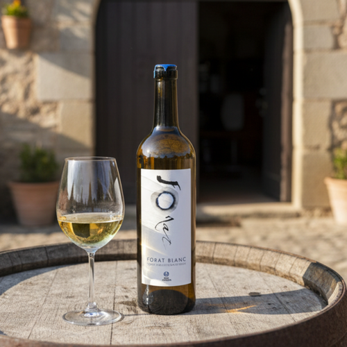 Bottle of white wine and glass on a wooden barrel with stone building in the background