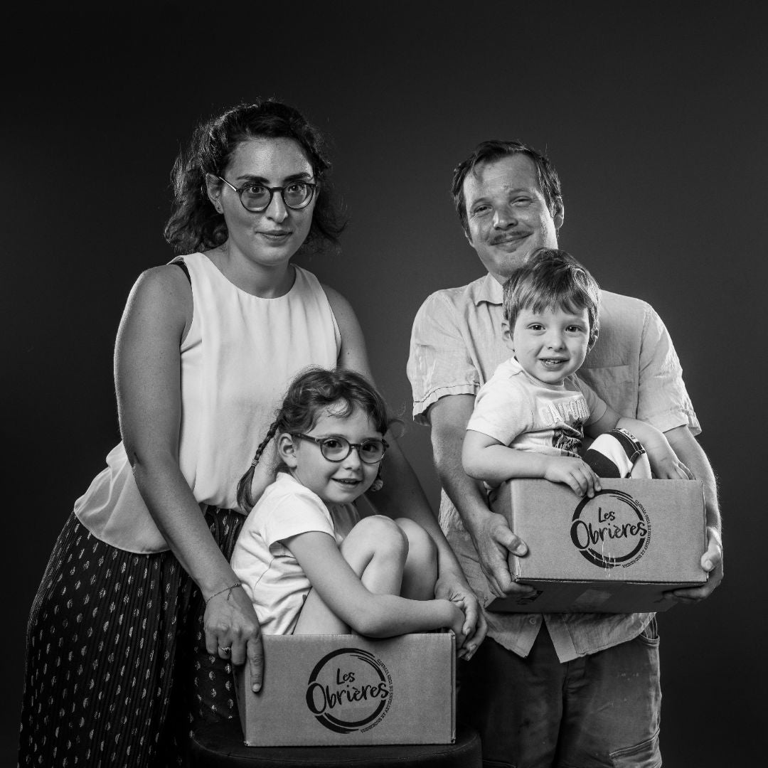 Black and white family portrait of Sarah and Charles from Domaine les Obrieres and two children holding boxes