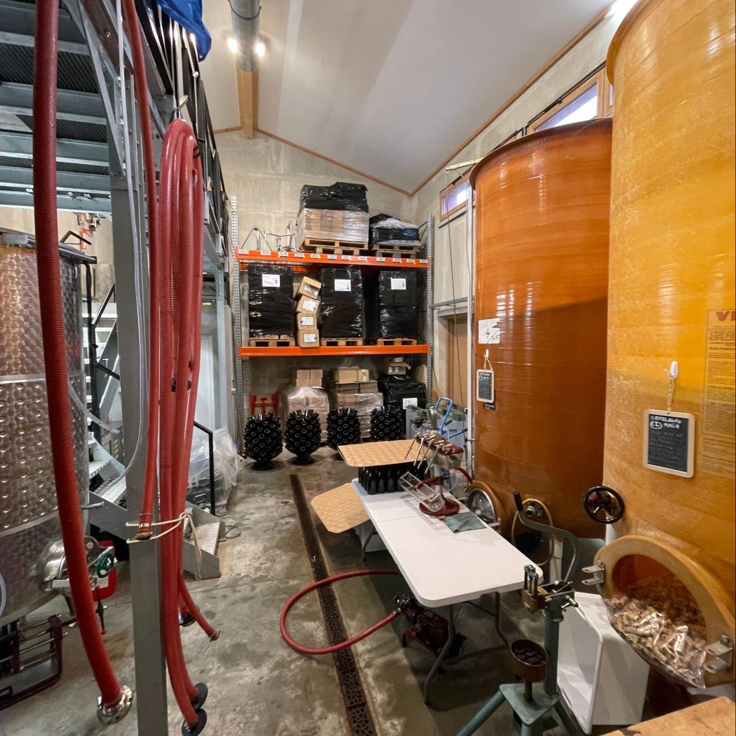Malia's cellar interior, with a large vat, hoses, and equipment