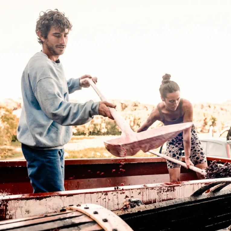 Two people unloading a boat from a truck in a natural setting