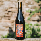 Wine bottle with a colorful label on a wooden surface with a blurred natural background