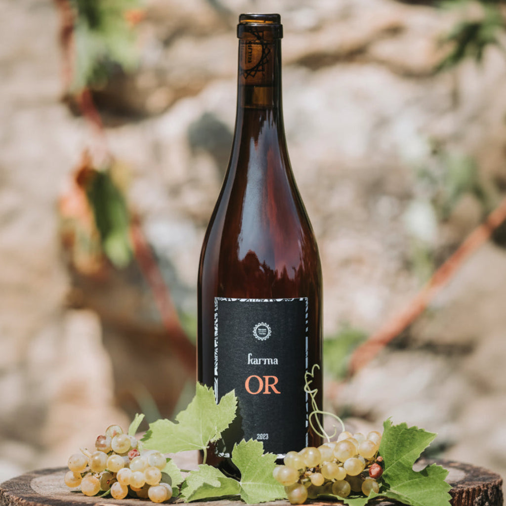 Wine bottle labelled 'Karma OR' with grapes on a wooden surface